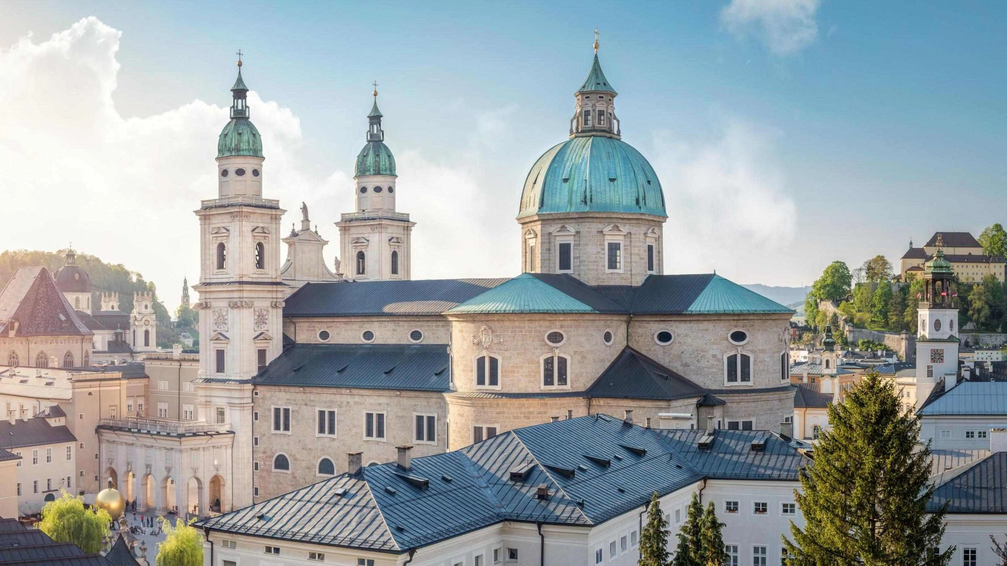 Aerial view of a historic cathedral with domes and steeples amid buildings at dusk.