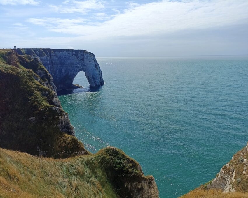 Cliff with a natural arch overlooking a blue sea.