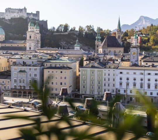 View of Salzburg cityscape with historic buildings and Hohensalzburg Fortress on the hill.