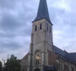 Old stone church with a tall spire against a cloudy sky.