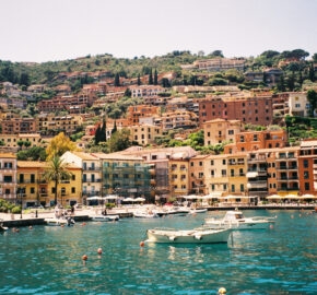 Coastal town with colorful buildings and boats on clear blue water.