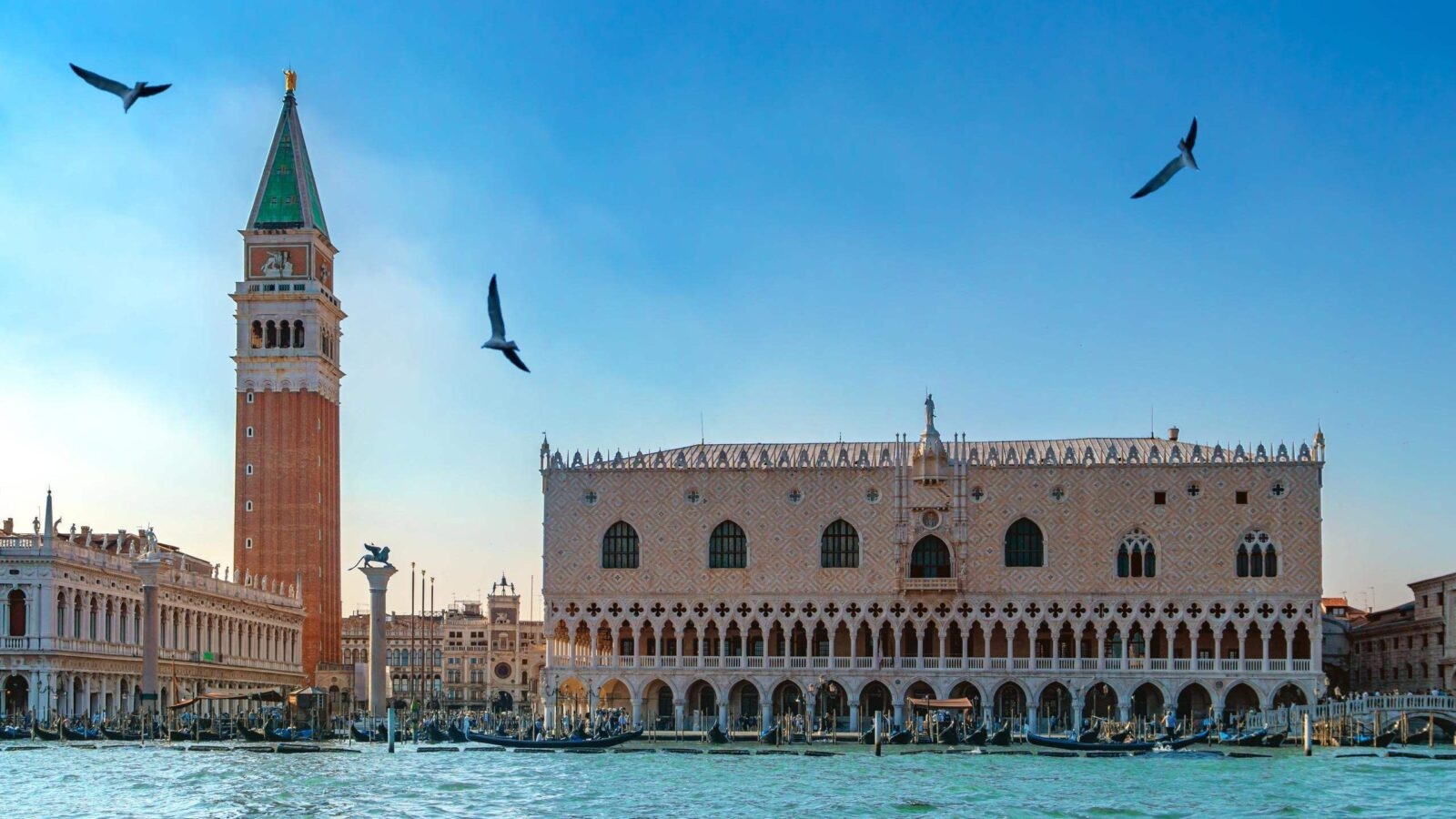 Venice skyline with Doge's Palace, Campanile, gondolas, and flying birds against a dusk sky.