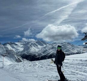 Skier standing on snowy mountain slope with scenic alpine background.
