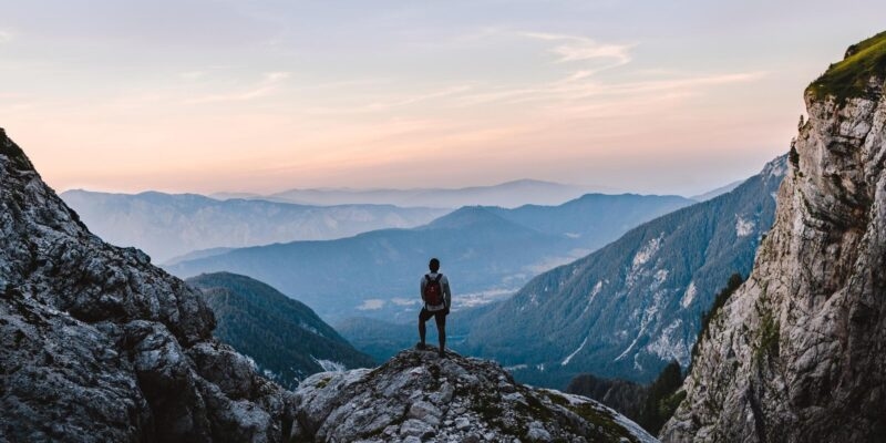 A solo hiker admiring the view from on top of a mountain