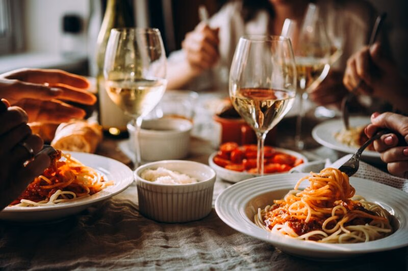People enjoying an Italian meal of pasta with wine