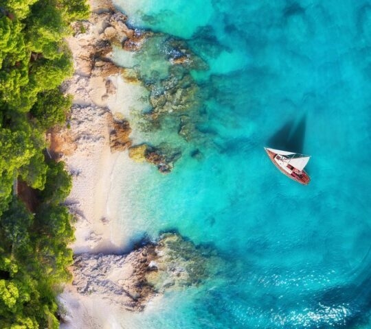 An aerial view of a sailing boat on turquoise waters in Croatia.