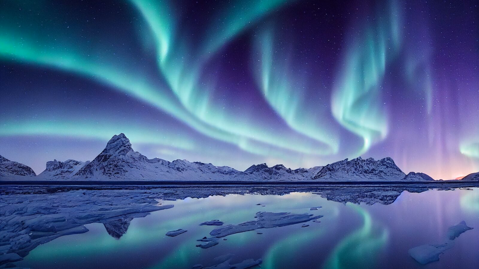 Blue and purple northern lights reflected over a lake