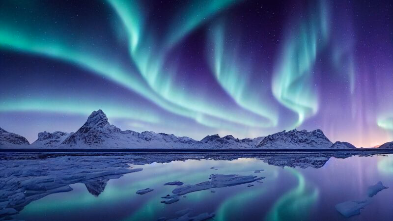 Blue and purple northern lights reflected over a lake
