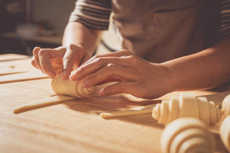 A pastry chef rolling croissants by hand