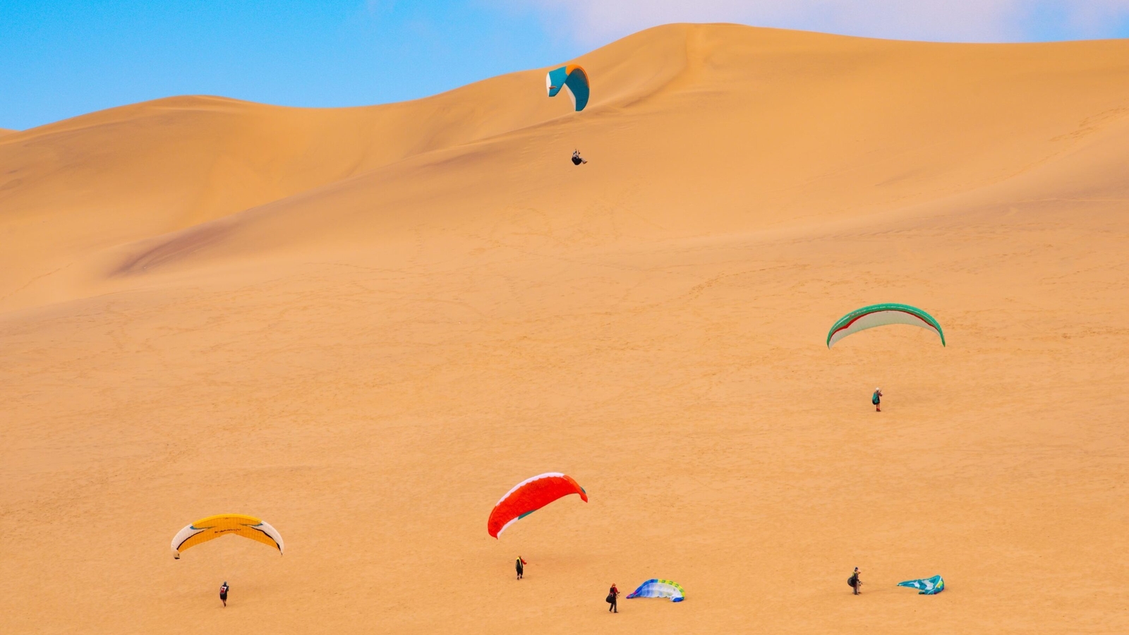 People paragliding on the dunes in Swakopmund, Namibia