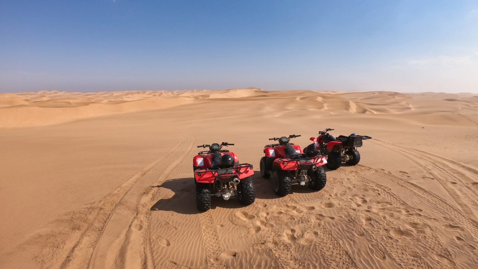 Three quad bikes parked side by side in the desert
