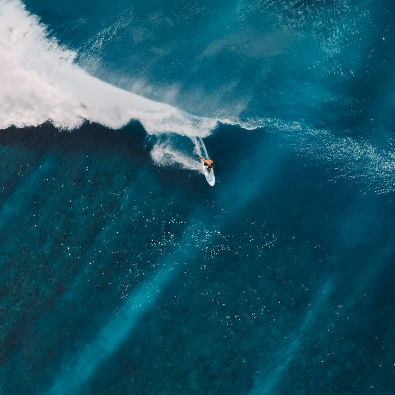 Aerial view of a man surfing on turquoise waves