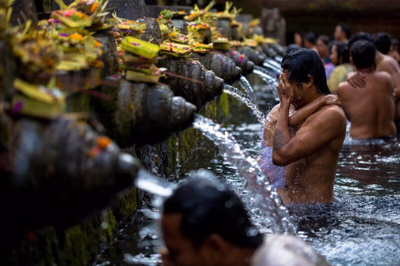 Men washing their faces at a water purification ceremony in Ubud, Bali