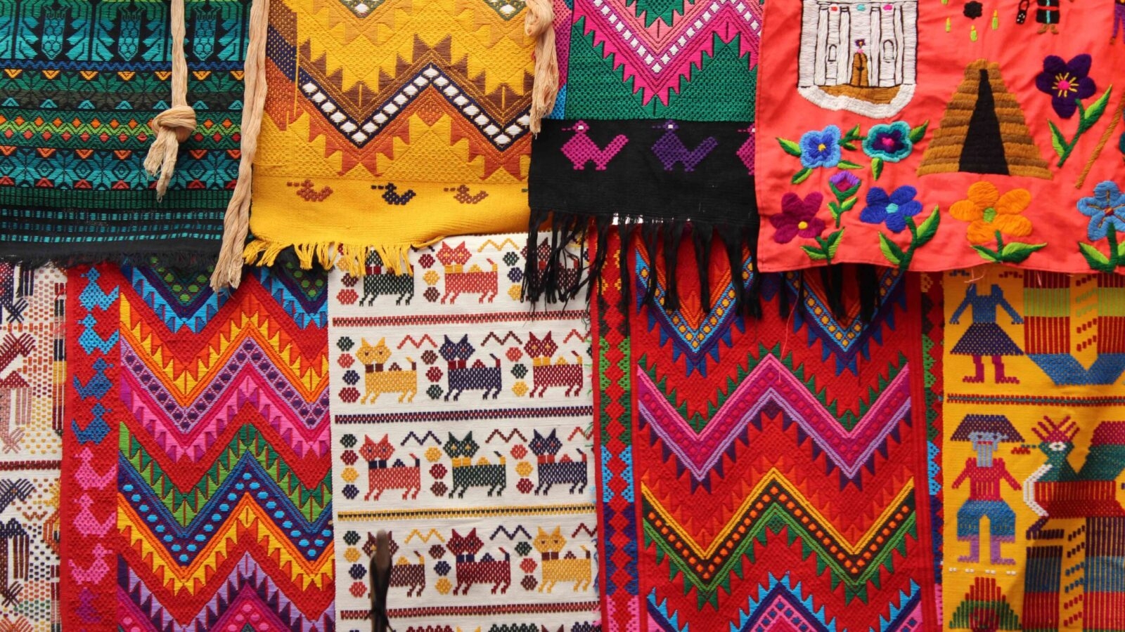 Close-up of vibrant, richly colored Guatemalan textiles hanging together with geometric and figurative woven patterns.