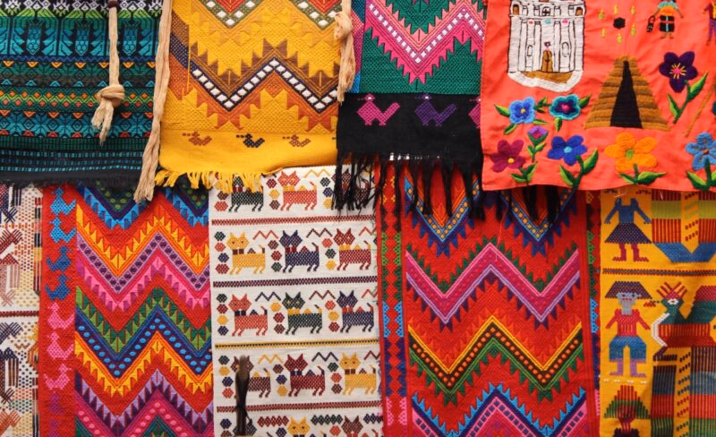 Close-up of vibrant, richly colored Guatemalan textiles hanging together with geometric and figurative woven patterns.