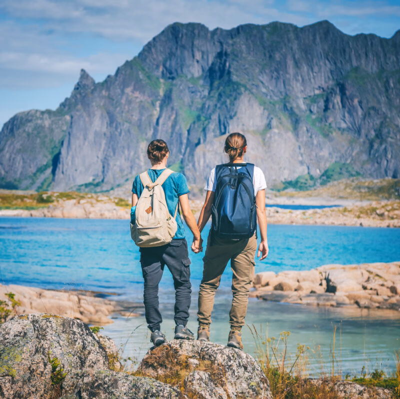 Two woman stand holding hands in Norway's Lofoten Islands