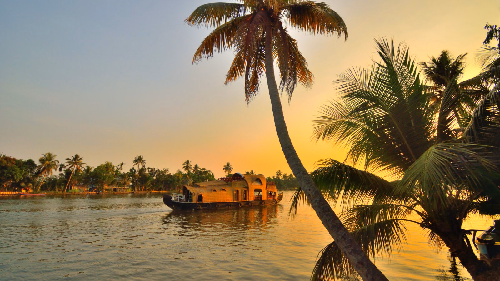 A boat sailing on Kerala backwaters during sunset.