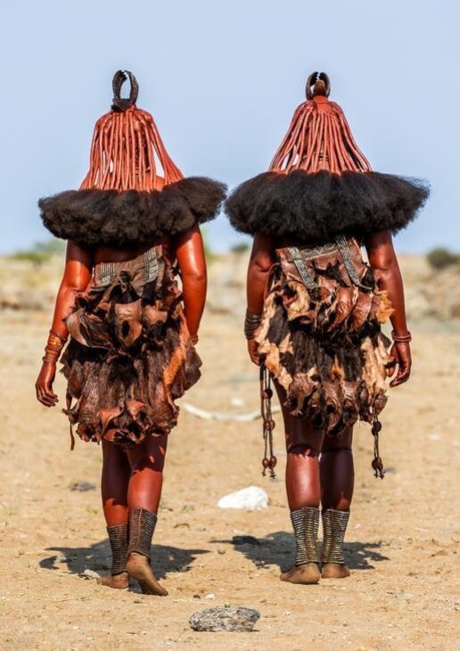 Two Himba people walking side by side, a man sells fruit at a market in Nairobi and a penguin colony on Boulders Beach.