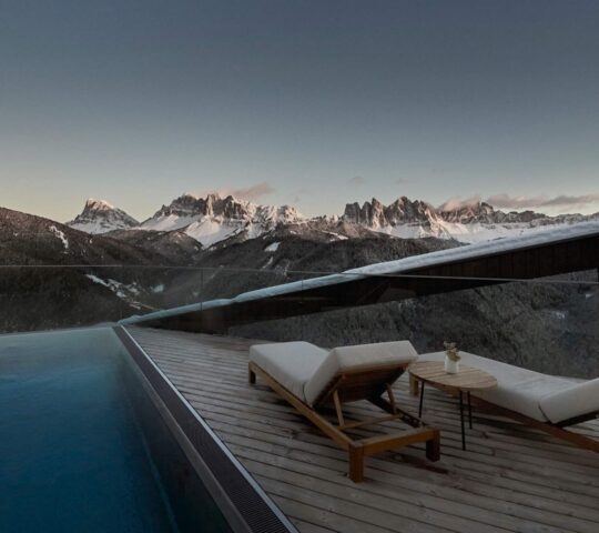 Two sun loungers next to a rooftop pool with mountain and forest views at Forestis Dolomites