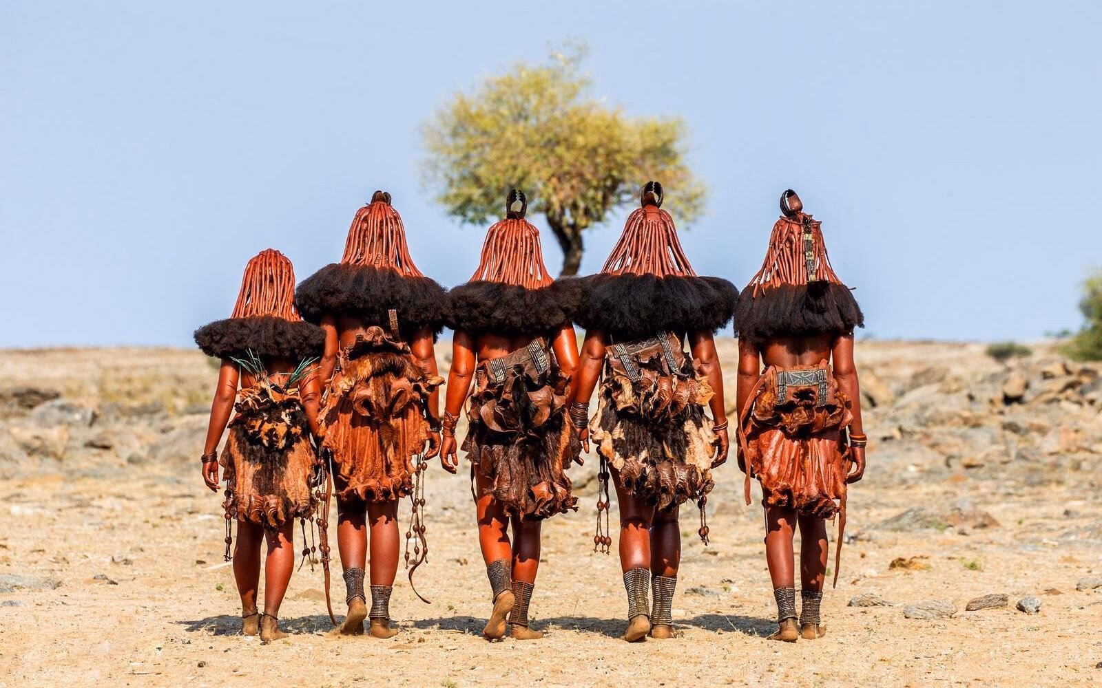 Himba women in traditional dress walking across the arid landscapes of northern Namibia.