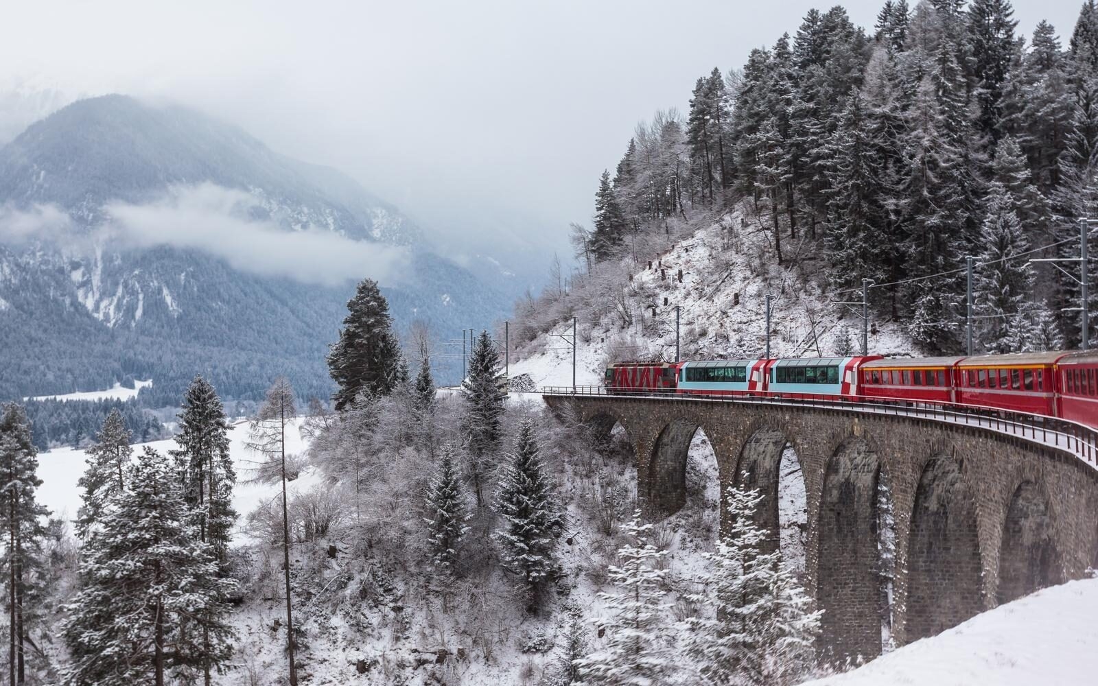 The Glacier Express crossing a stone viaduct in the Swiss Alps.