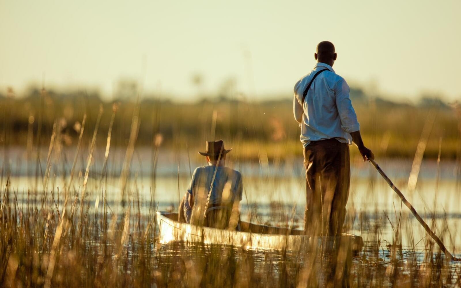 A guides steers a mokoro canoe through the Okavango Delta
