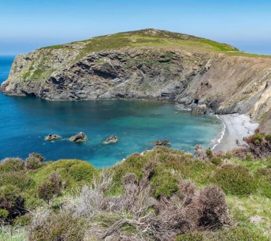 A bay with blue water and rocky cliffs on Ramsey island in Wales