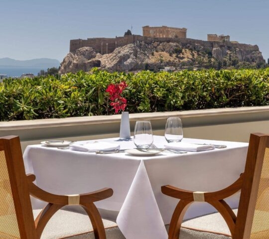 Outdoor terrace with dining table and view of the Acropolis at Grand Hotel Bretagne
