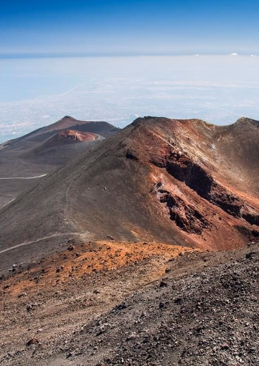 Refreshing summer hikes on Mount Etna in Sicily, the turquoise cove of Polignano a Mare in Puglia, and the island church on Lake Bled in Slovenia.
