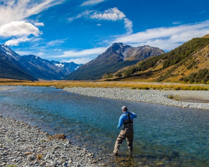 A fly fisherman casting on a mountain stream in New Zealand