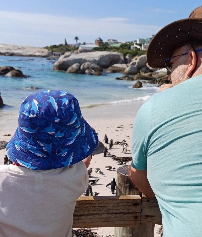 A father and son watch the penguins at Boulder's Beach in Cape Town.