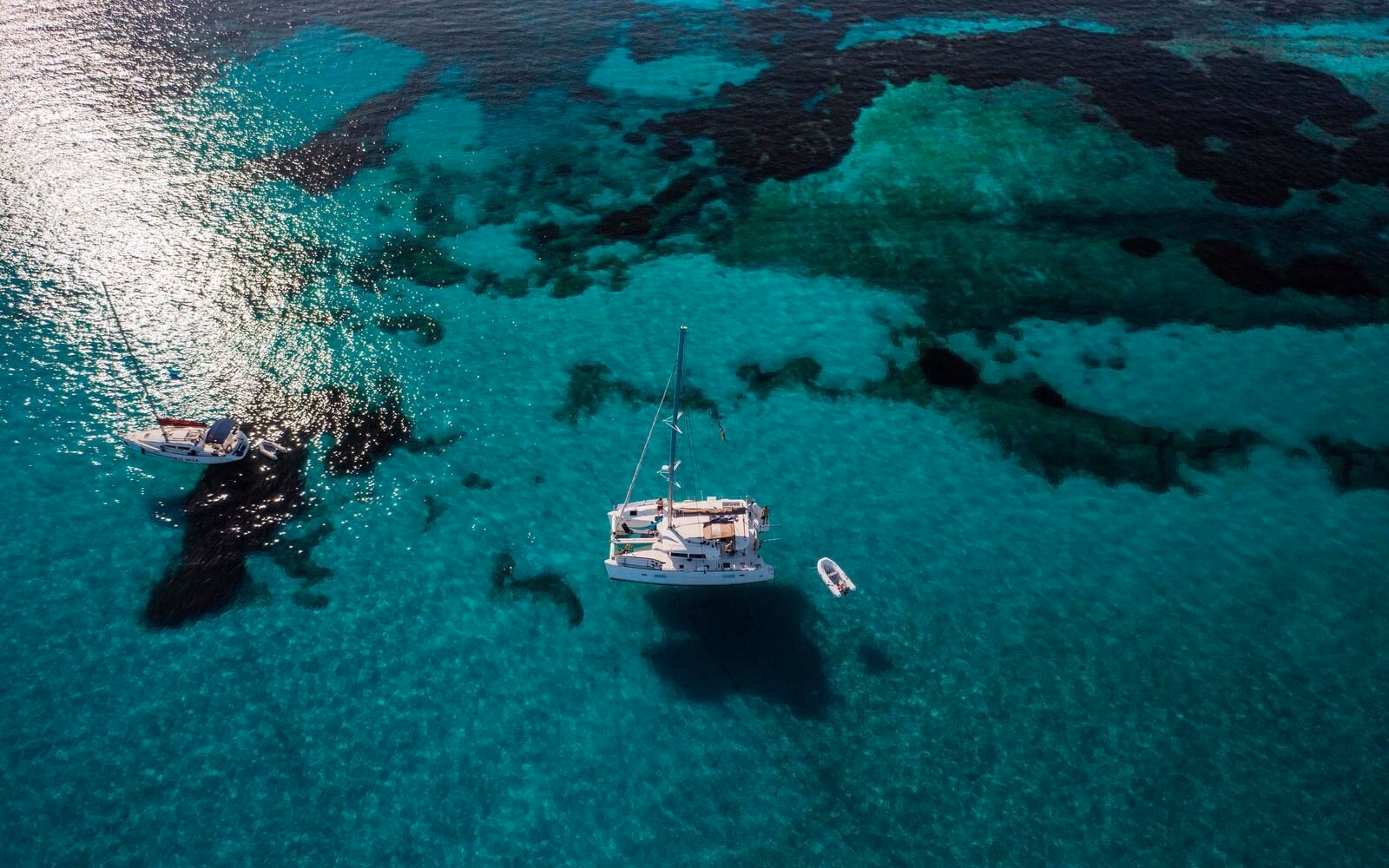 Clear turquoise waters and wildlife-rich reef systems in the Seychelles, where private yachts appear suspended in the air