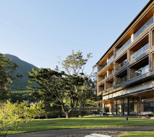 Exterior view of a modern hotel with a mountain and trees in the background