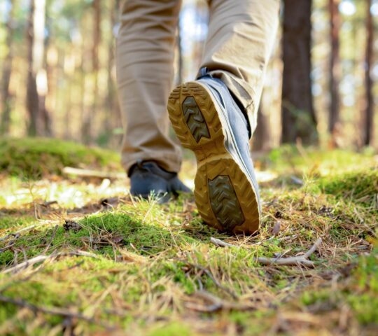 A close up of a person walking in a forest.