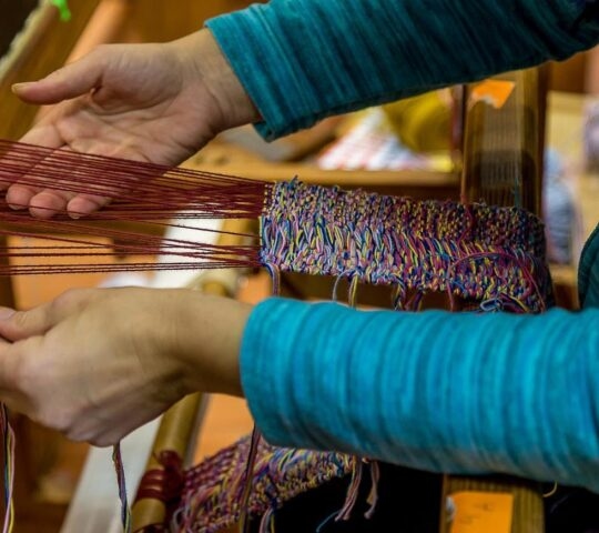 A person using a weaving loom.