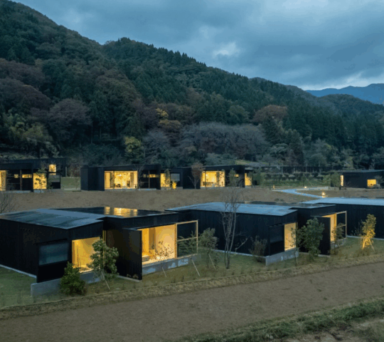 Wide view of low modern buildings at dusk with mountains behind them