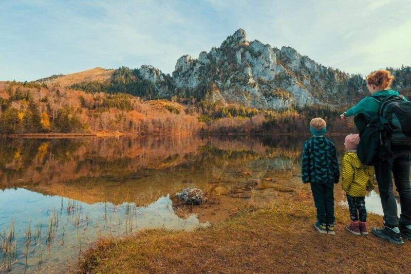 Mum and kids at the shore of the Laudachsee, Austria, with the stunning Katzenstein rising in the background and reflecting in the crystal clear water