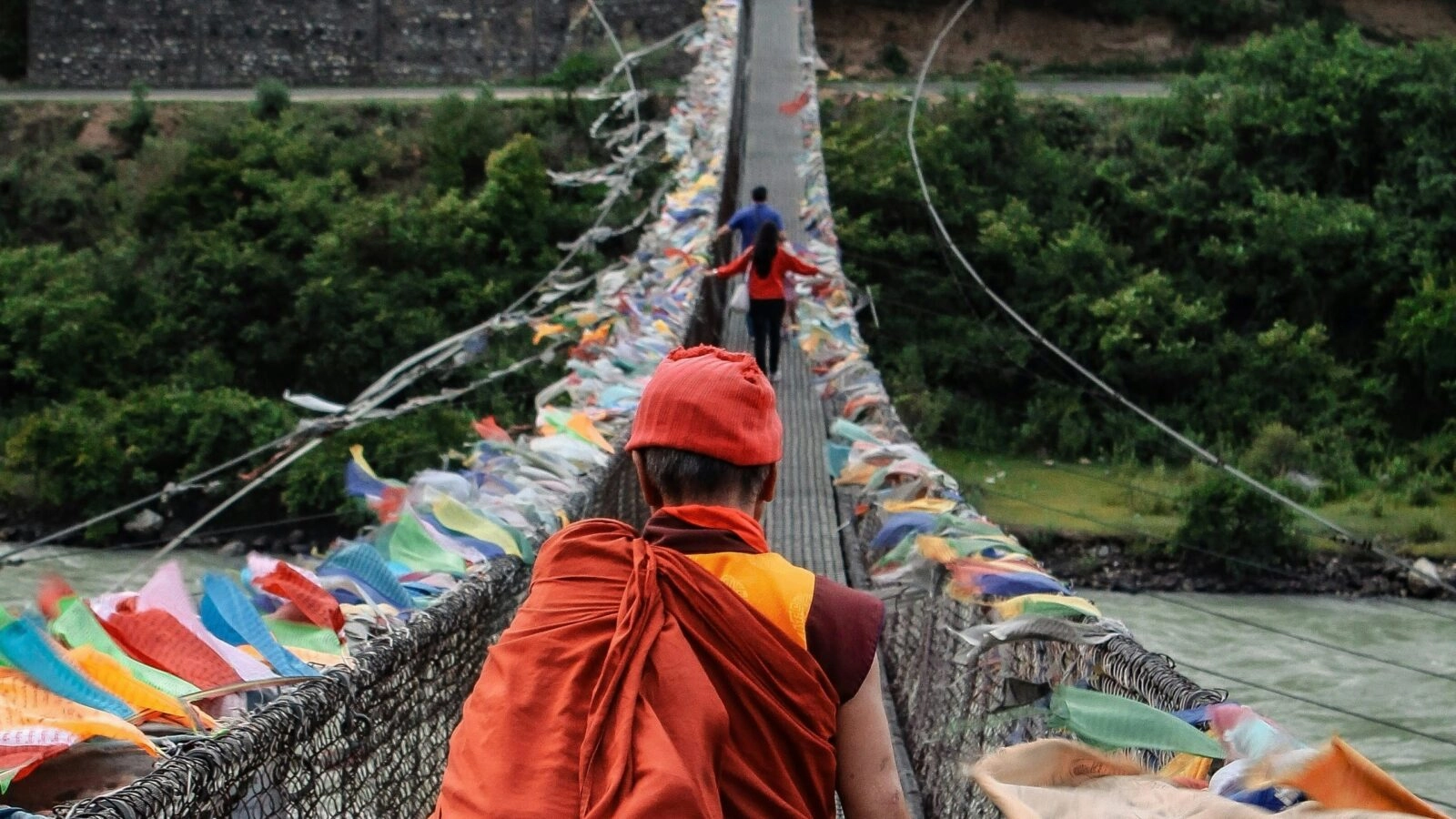 A family in Bhutan crossing the bridge with traditional flags