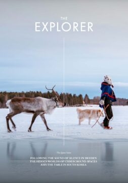The front cover of The Explorer, Issue 18 (space). A member of the Sami community in Sweden walking with a reindeer and a dog.