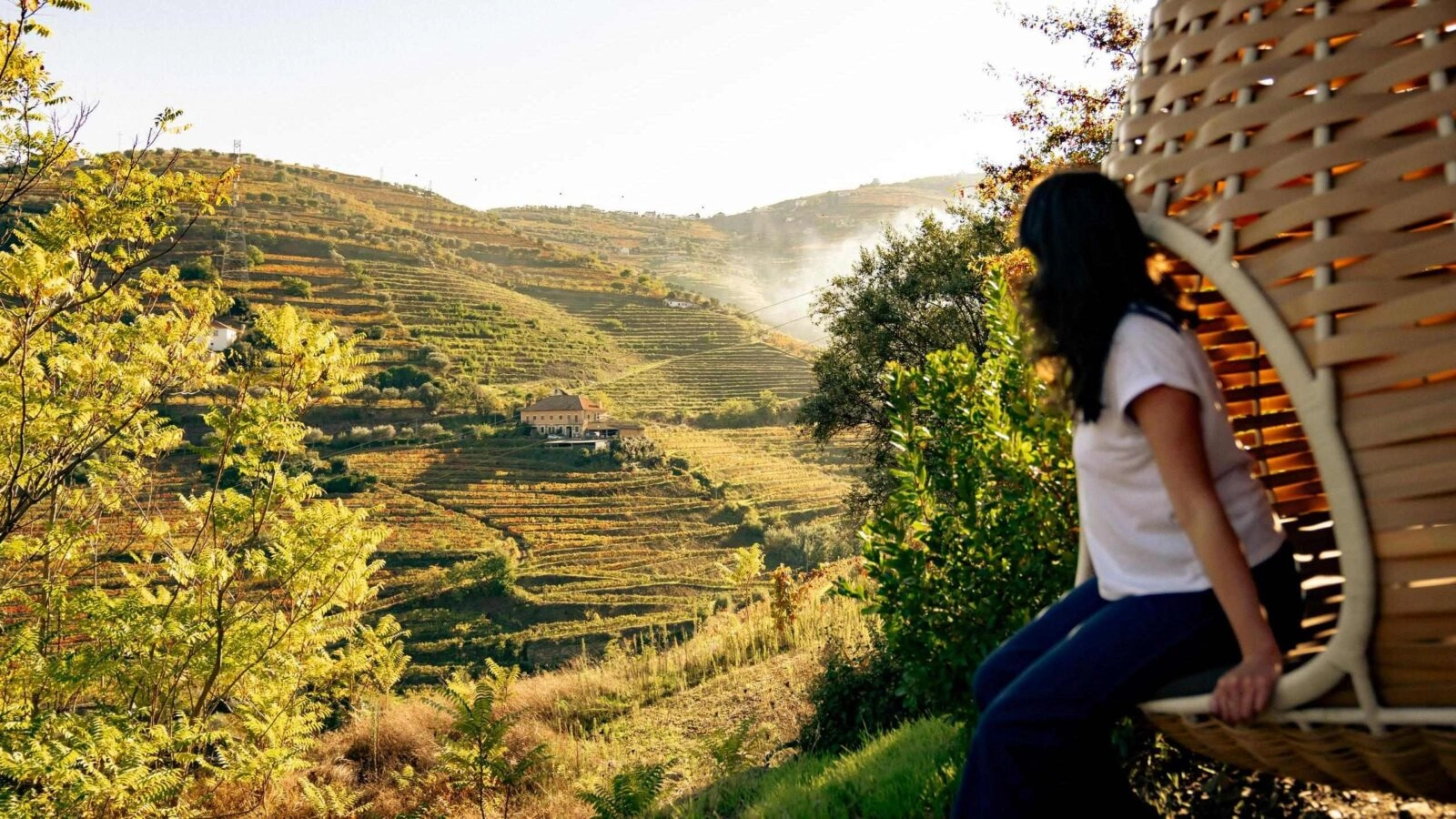 A women in a hanging chair overlooking the vineyards of Portugal's Douro Valley.
