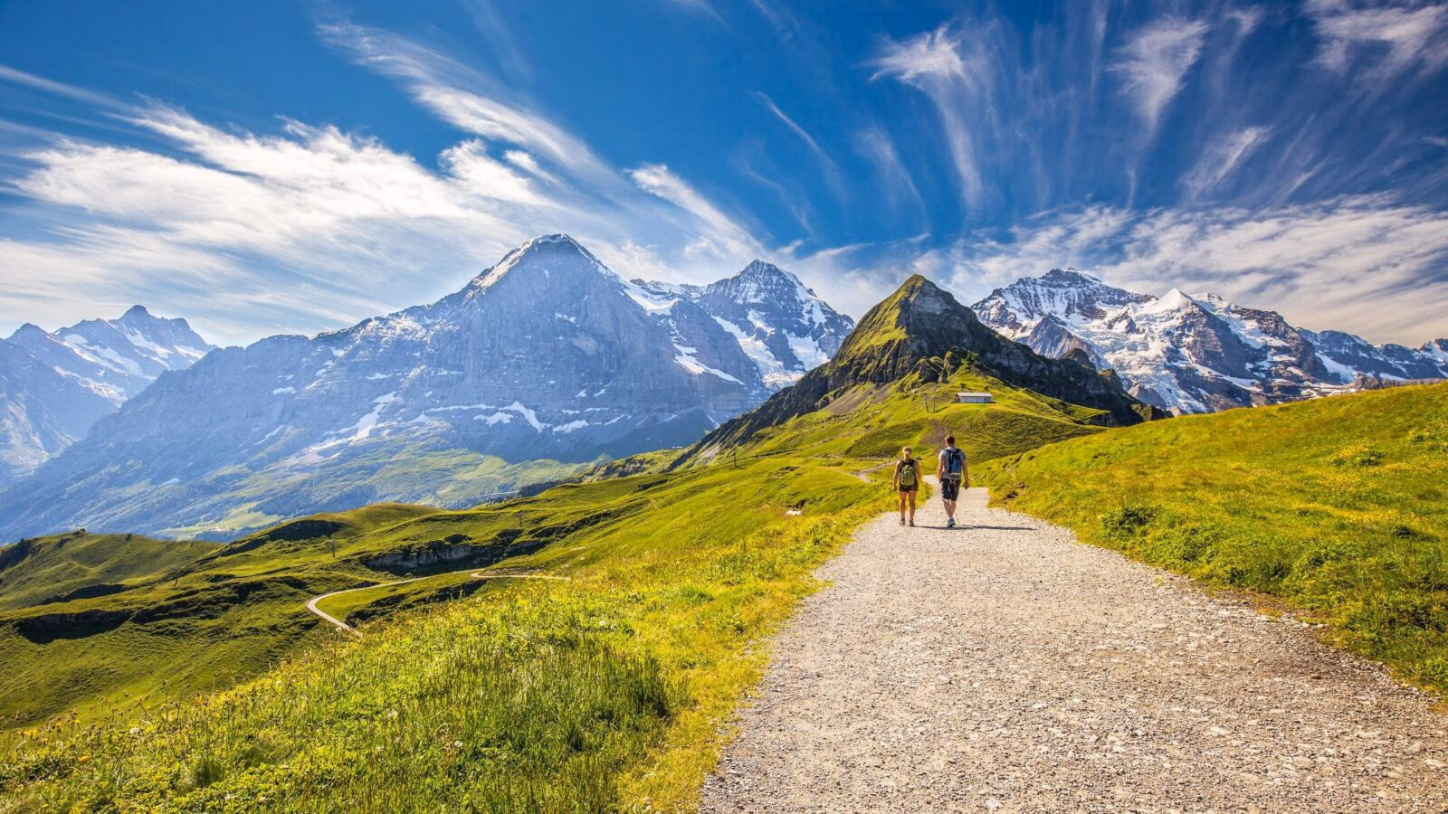 Young couple hiking in panorama trail leading to Kleine Scheidegg from Mannlichen