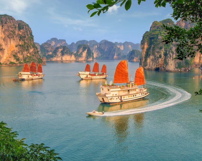 View of boats with orange sails sailing through Ha Long Bay in Vietnam