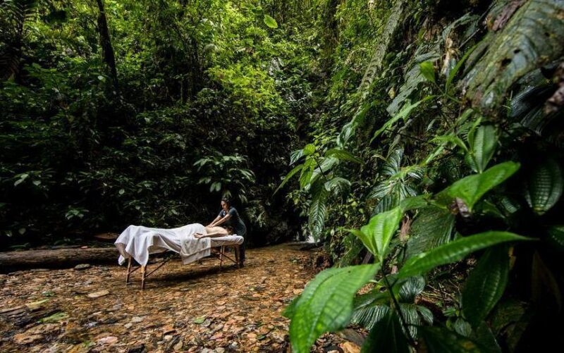 Woman receives a massage outside in the Ecuador cloud forest by a waterfall with trees all around