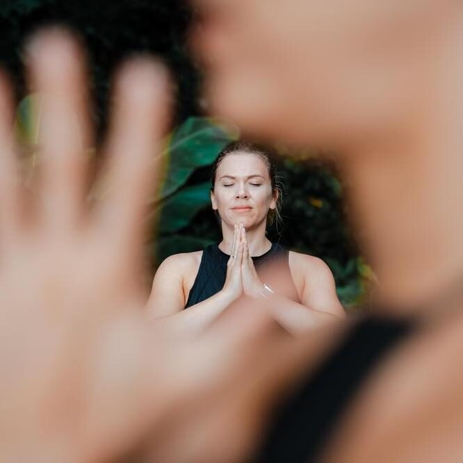 Woman in prayer stance during yoga practice looking at peace in nature