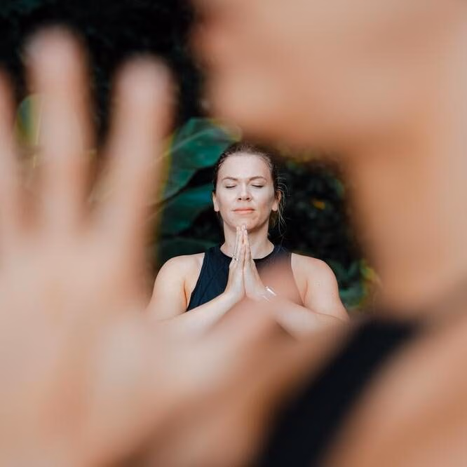 Woman in prayer stance during yoga practice looking at peace in nature