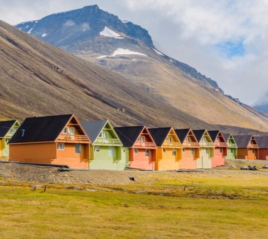 A row of colourful cabins in Longyearbyen, Svalbard set against a mountain peak.