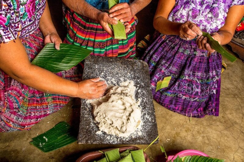Mayan women in traditional wear preparing food together