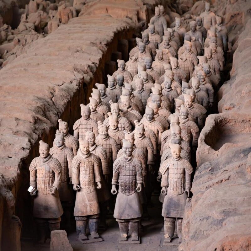 terracotta warriors stood in rows in the ground in China