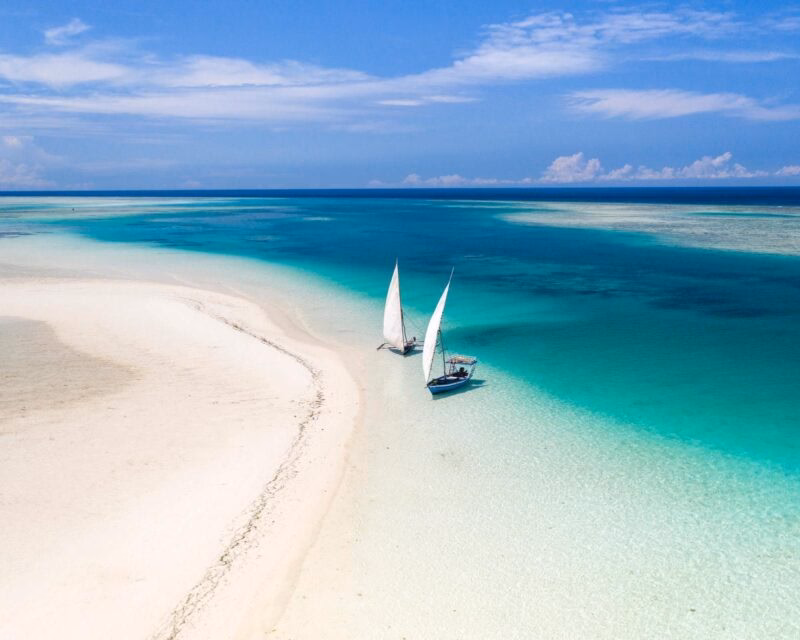 Aerial view of a sandbank with two sailboats in turquoise water in Zanzibar
