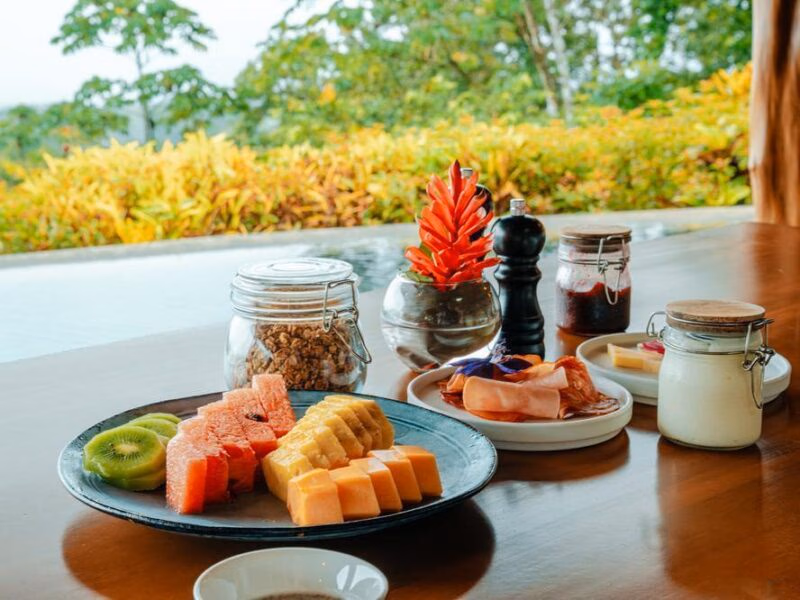 A fresh breakfast spread of tropical fruits and granola jars on a wooden table during luxury Family trips.